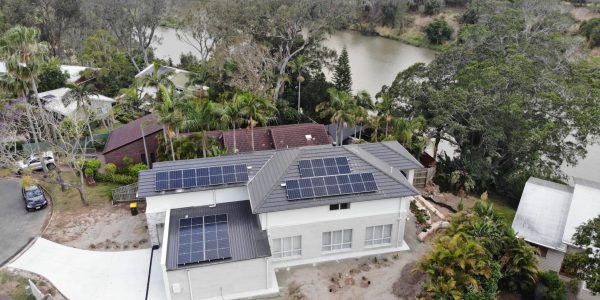 Large residential solar system on a white home with a river behind it
